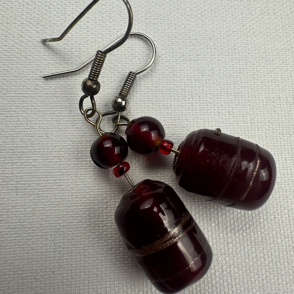 Costume jewelry dark red glass bead with gold stripe dangle earrings.